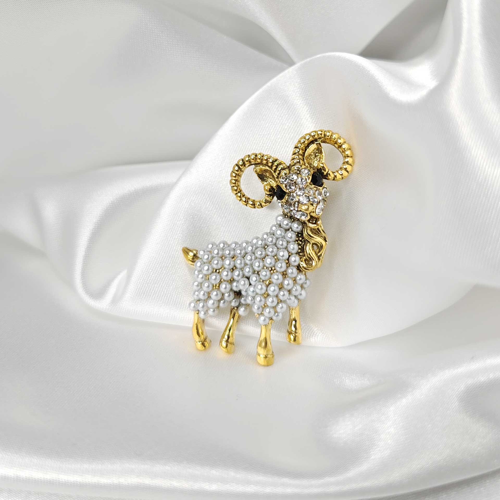 Photo de la broche dorée en forme de bélier ornée de perles.