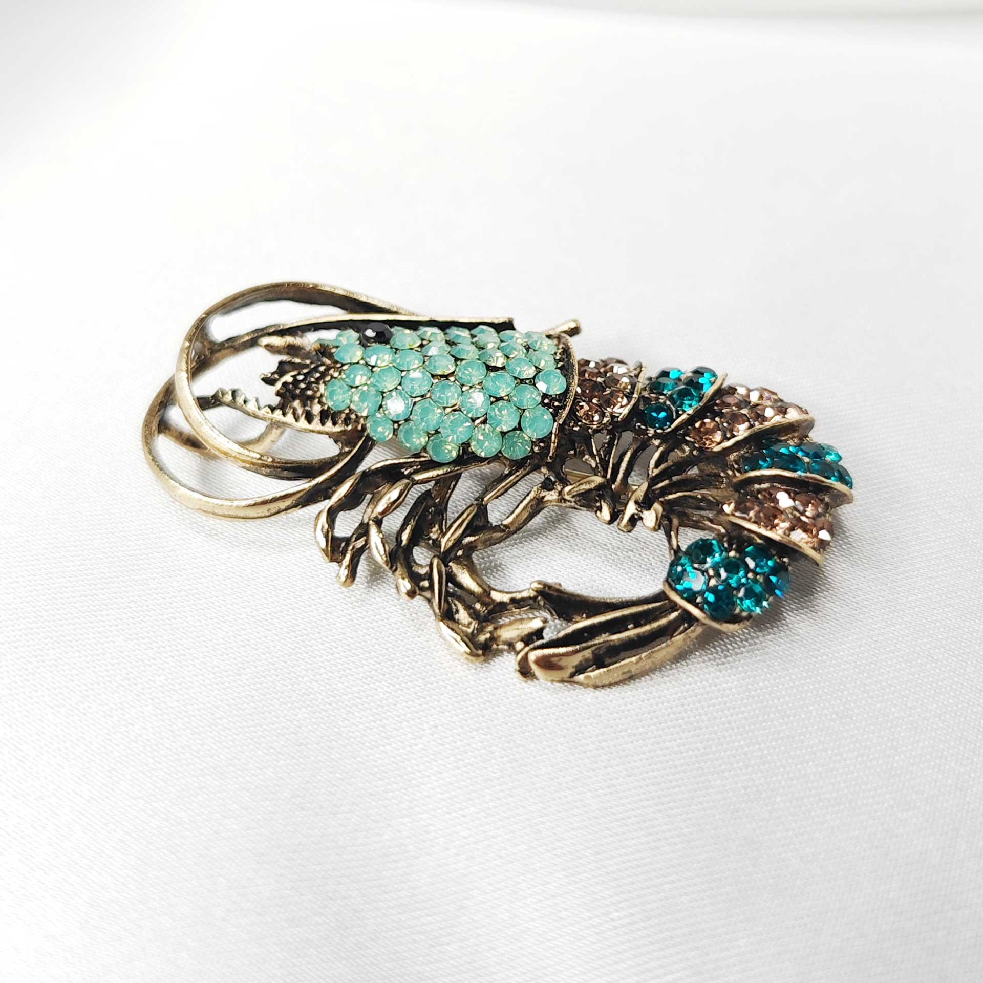 Photo 3 Détail rapproché de la broche crevette bleue, révélant la finesse des antennes et l’éclat des pierres.