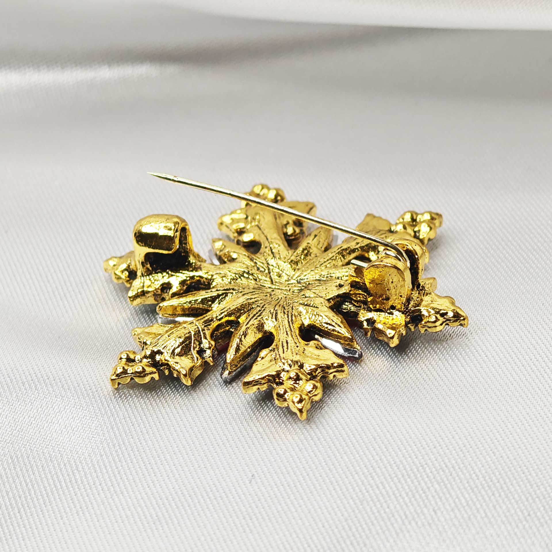 Broche bijou étoile de noel fleur de Poinsettia vue zoom sur l'épingle à nourrice ouverte.