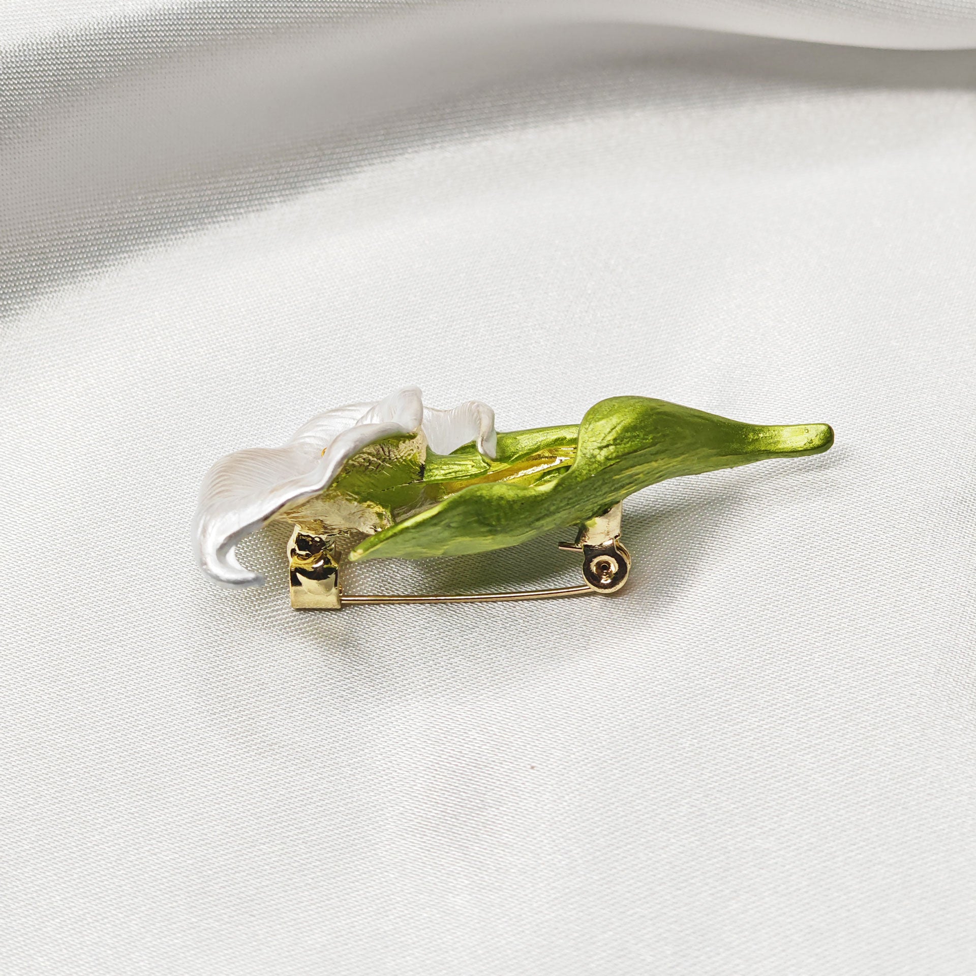 Broche arum blanc vue de côté avec épingle dorée et feuille verte
