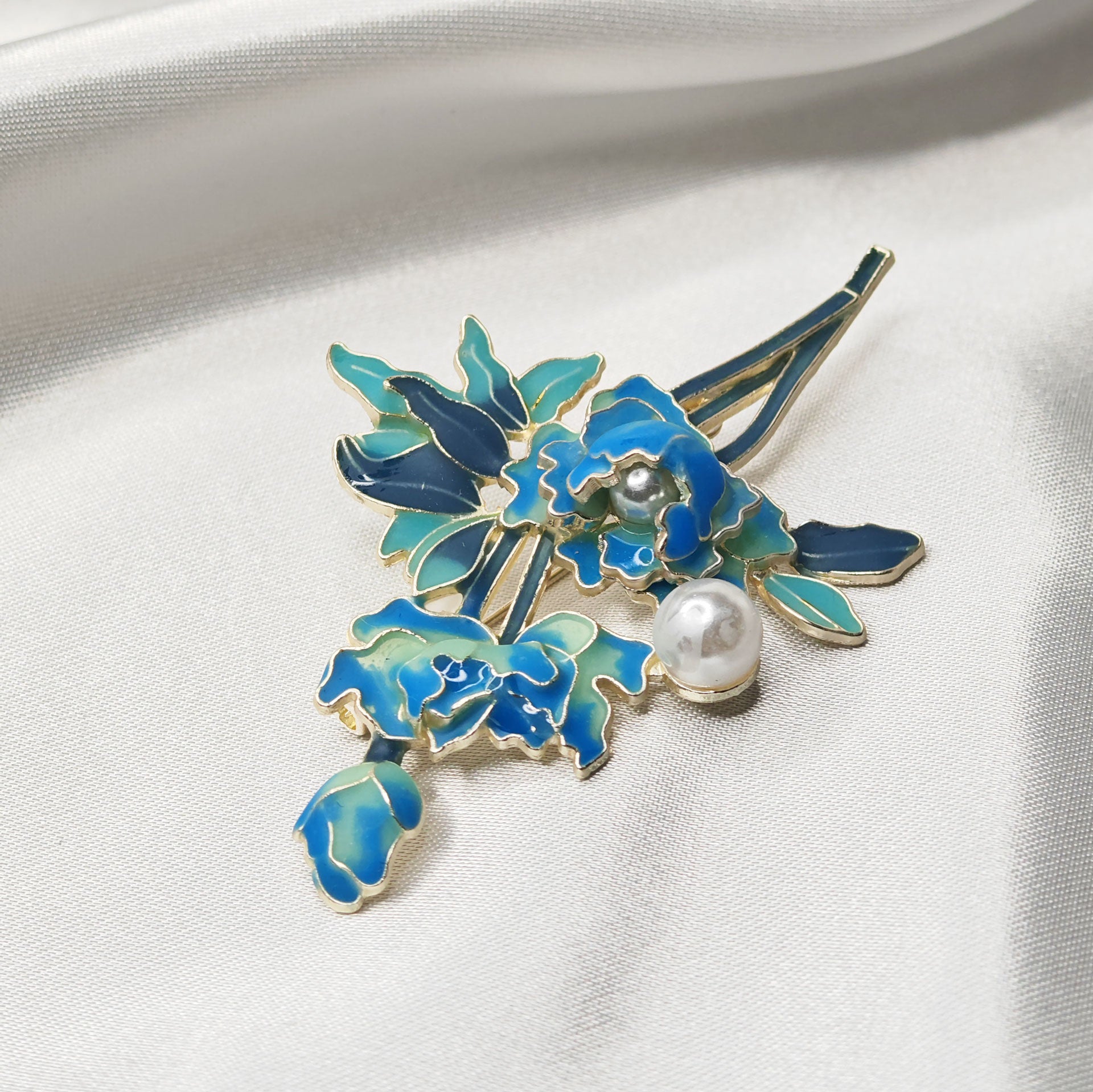 Détail broche bijou pivoine bleue émaillée et perle vue de dessus.