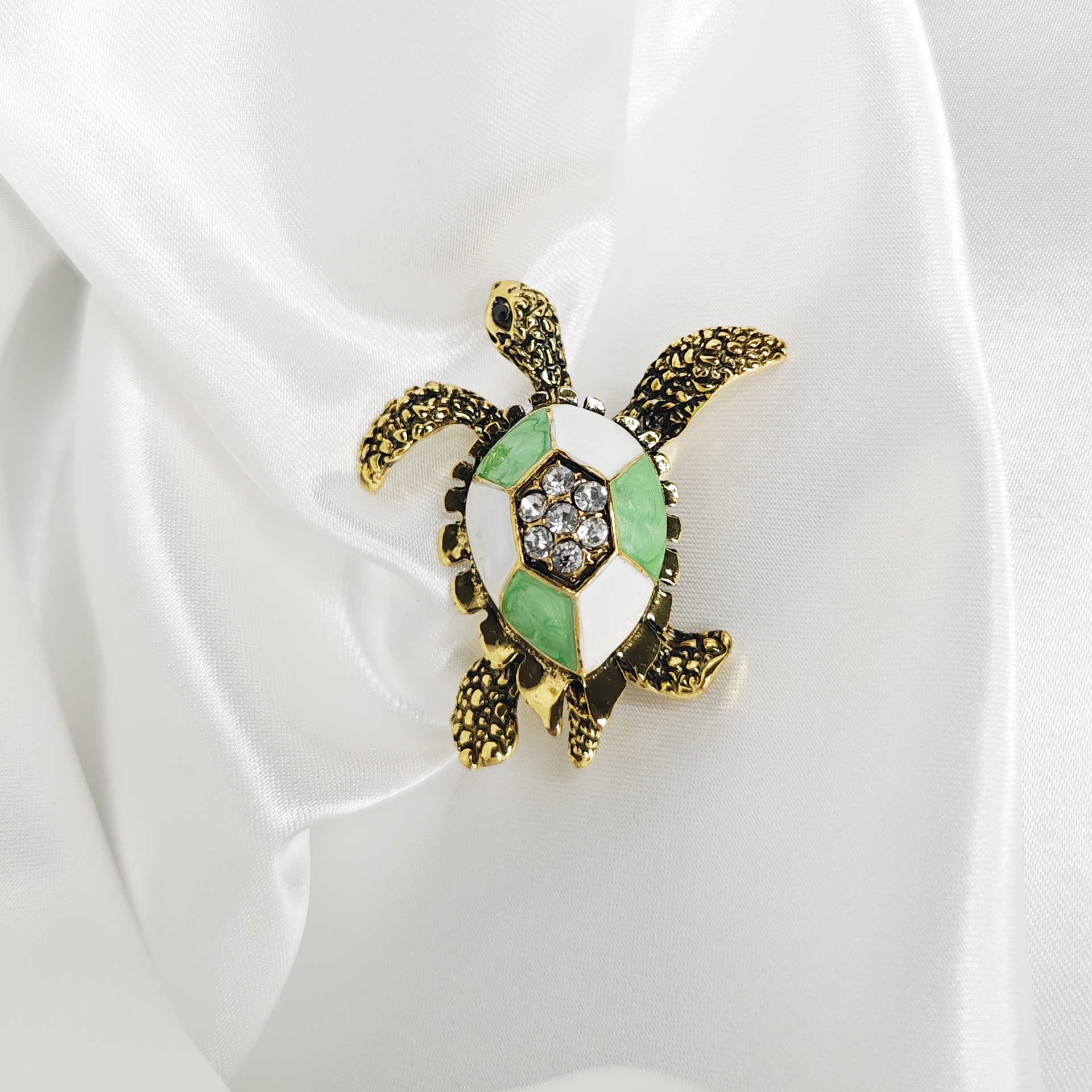 Photo principale de la broche tortue de mer finition vintage avec une carapace blanche et verte.