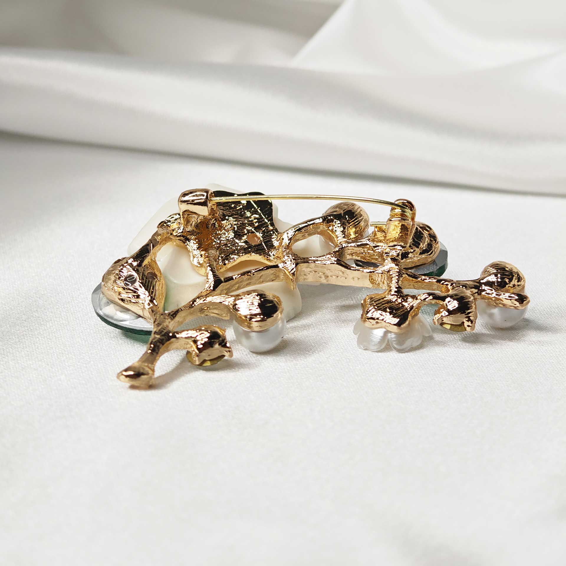 Photo verso de la Broche fleur de cerisier sakura sur branche ornée de perles et cristaux verts.