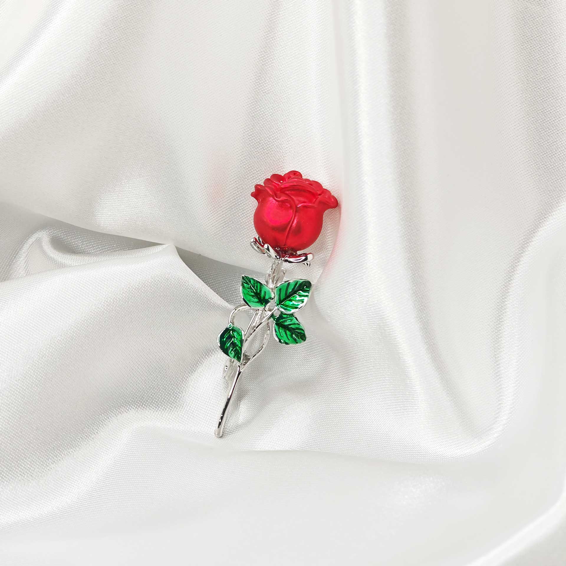 Photo vue de face de la broche rose rouge et pétales vertes