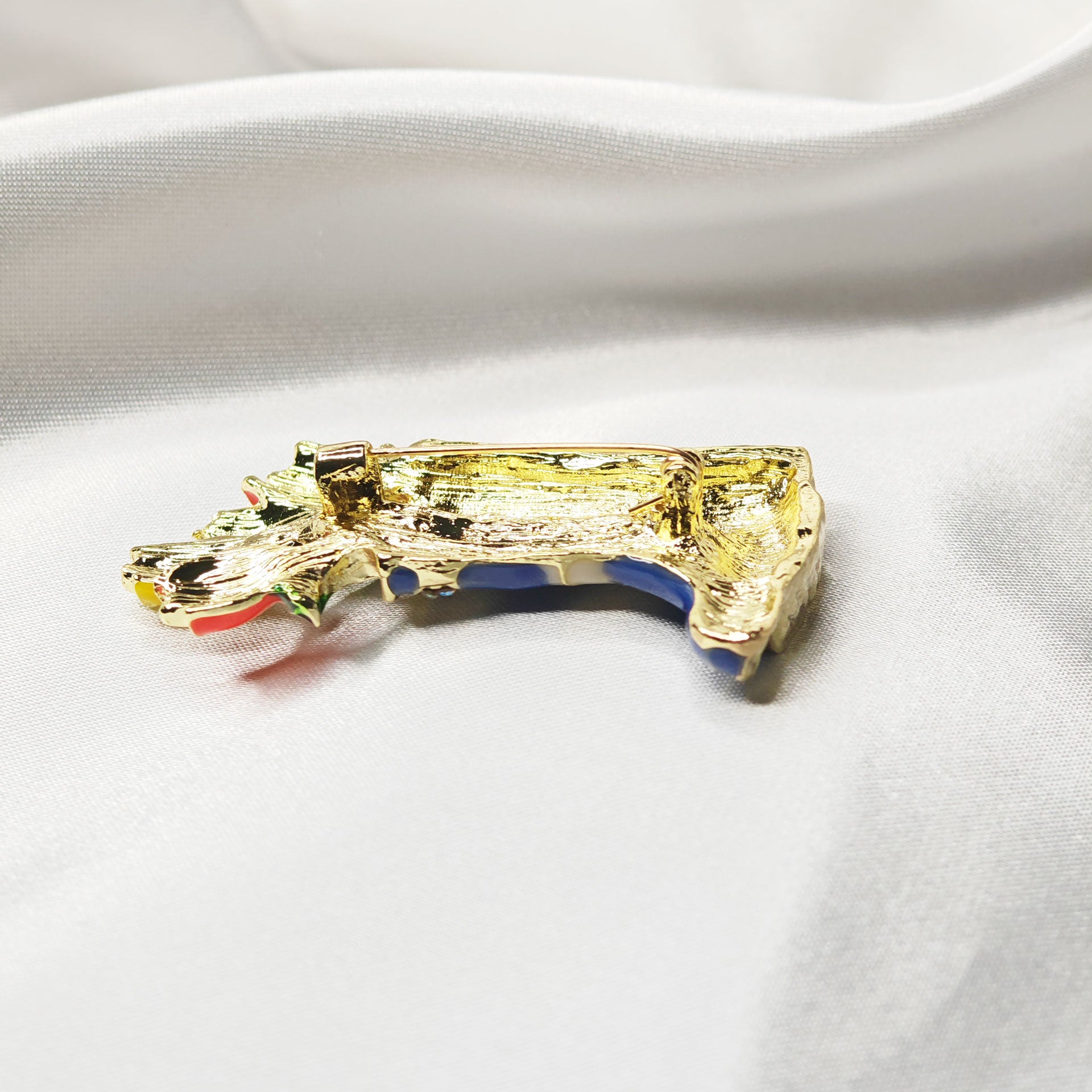 Broche bijou bottes de pluie bleues avec fleurs multicolores vue sur l'épingle à nourrice.