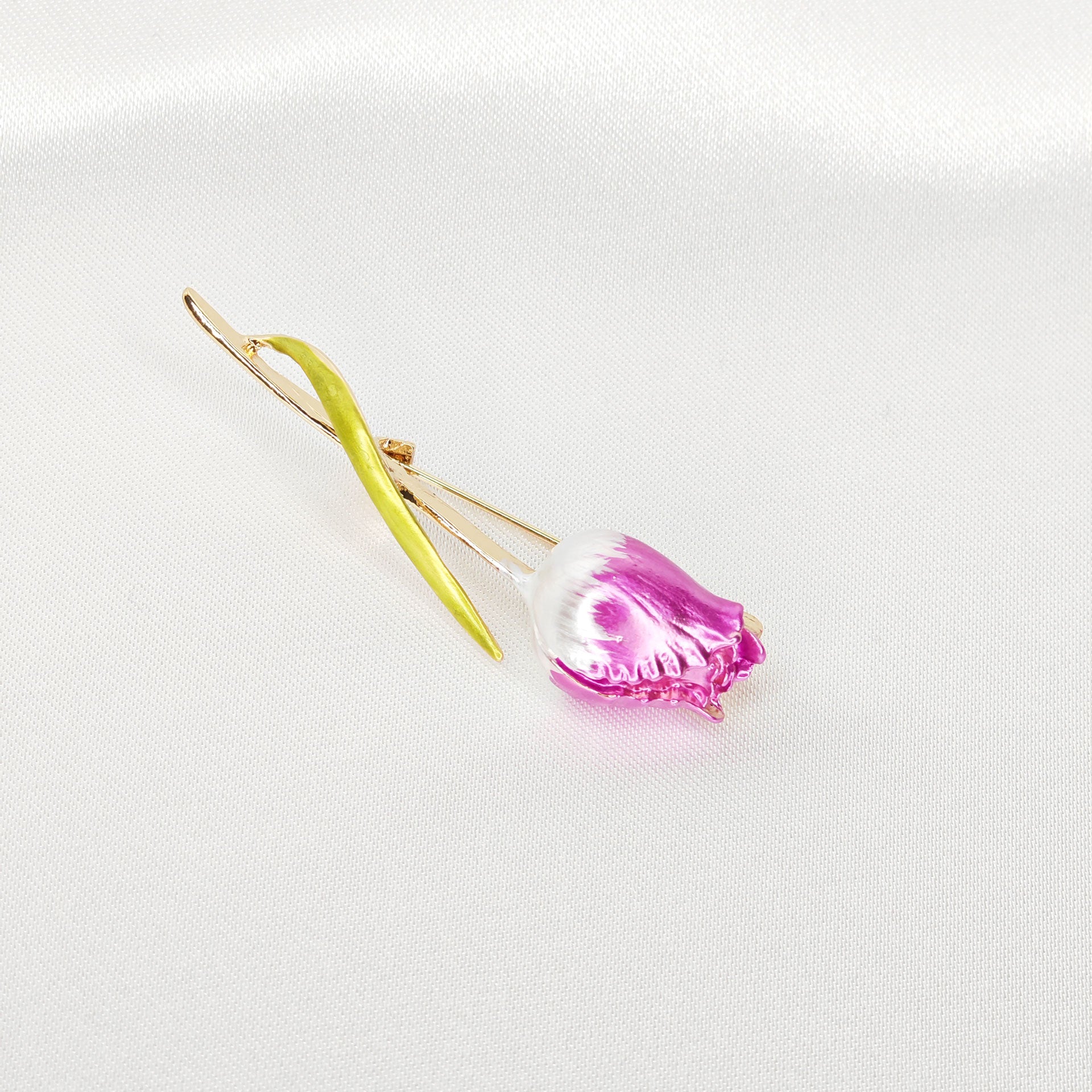 Broche tulipe rose avec finitions dorées sur fond blanc.