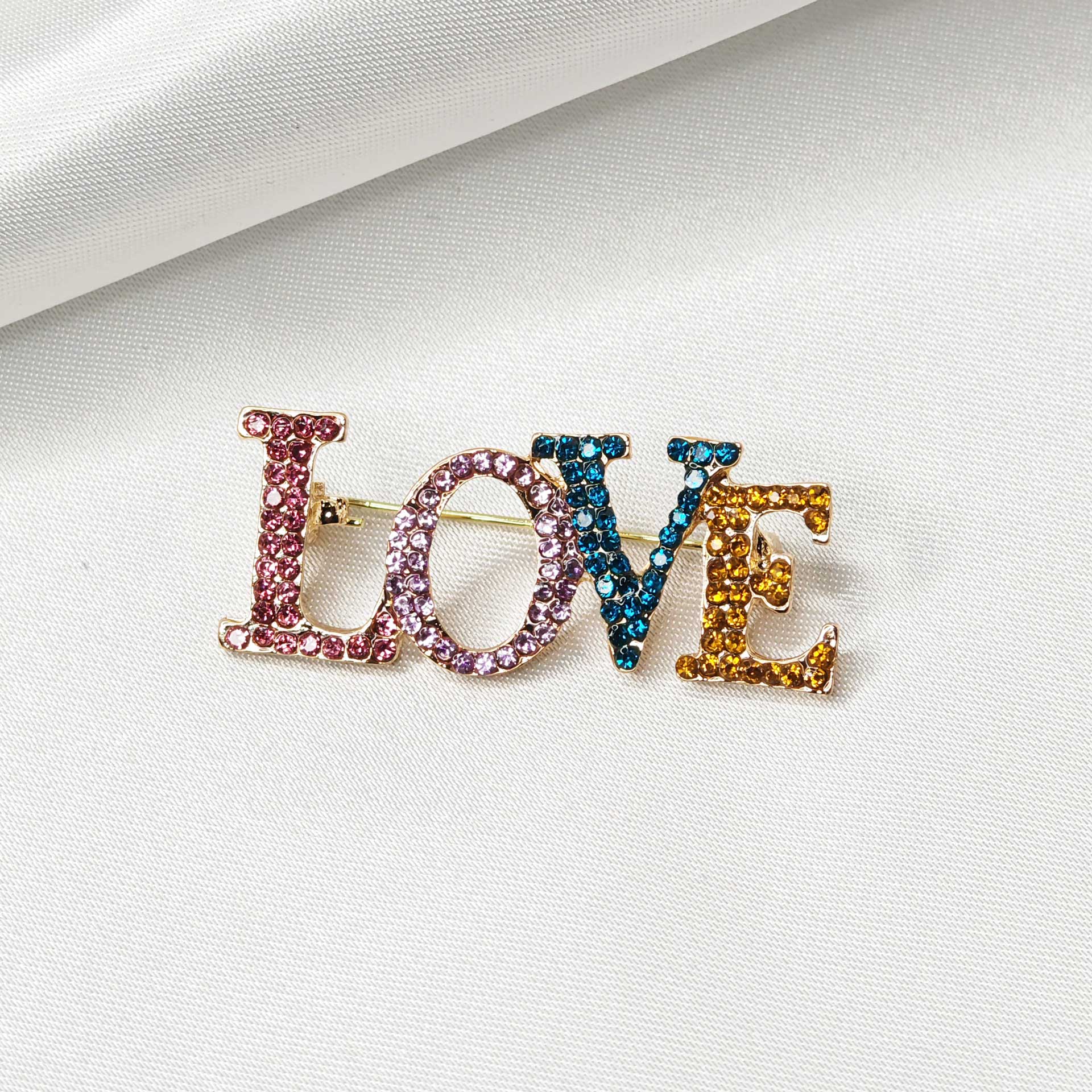 Photo de face de la broche LOVE en écriture capitale et multicolore.