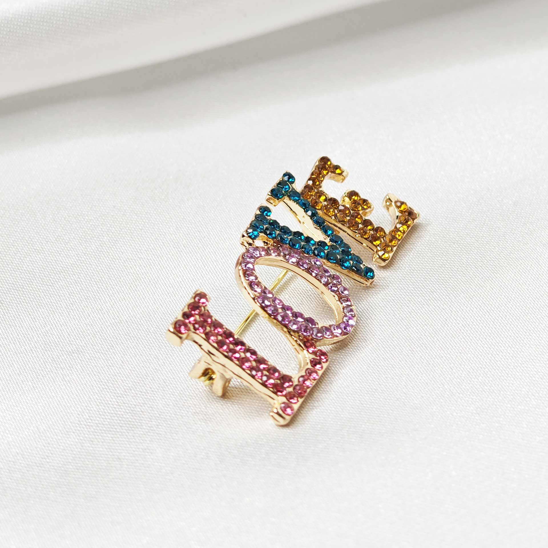 Photo de latérale gauche de la broche LOVE en écriture capitale et multicolore.