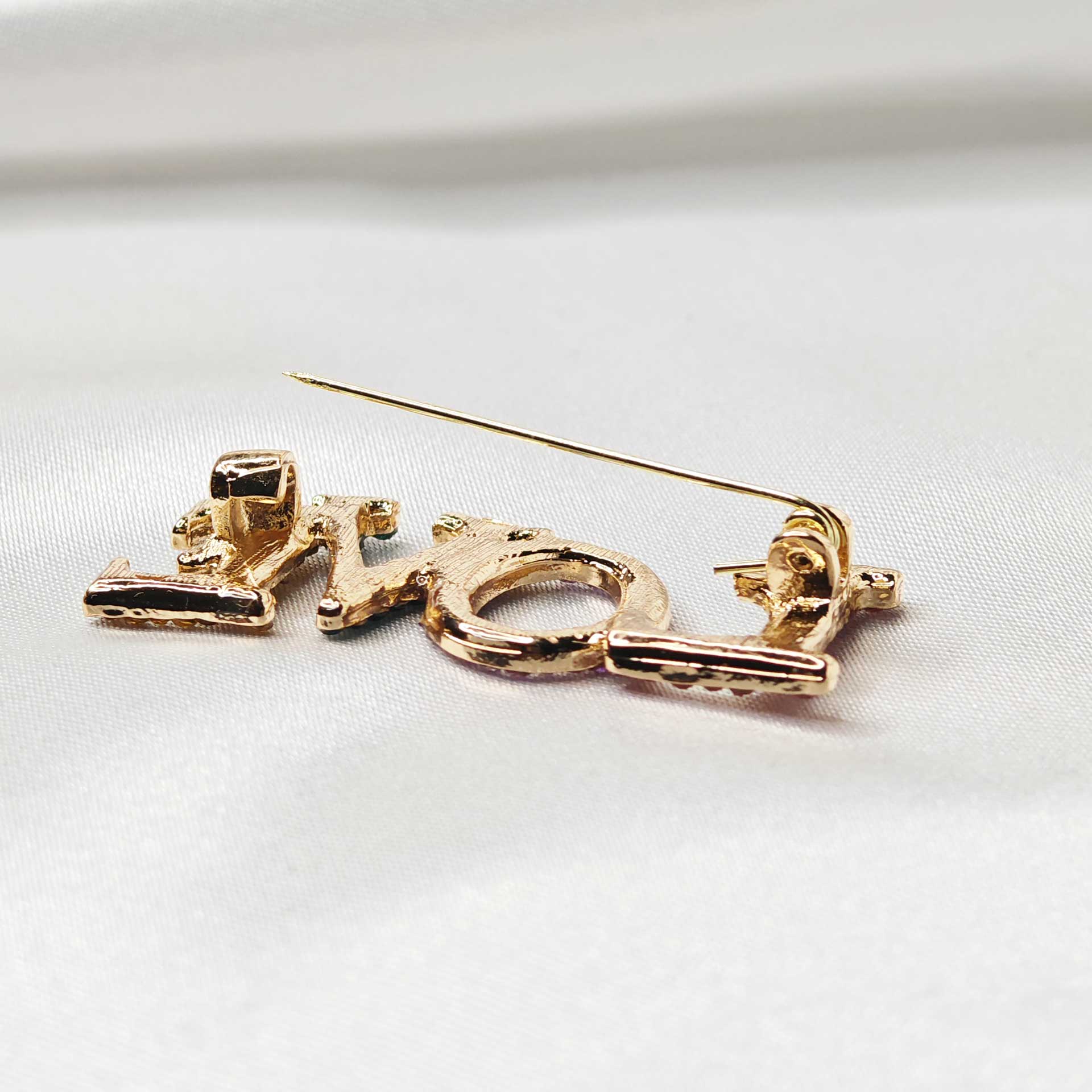 Photo du verso de la broche LOVE avec zoom sur l'attache épingle à nourrice ouverte.