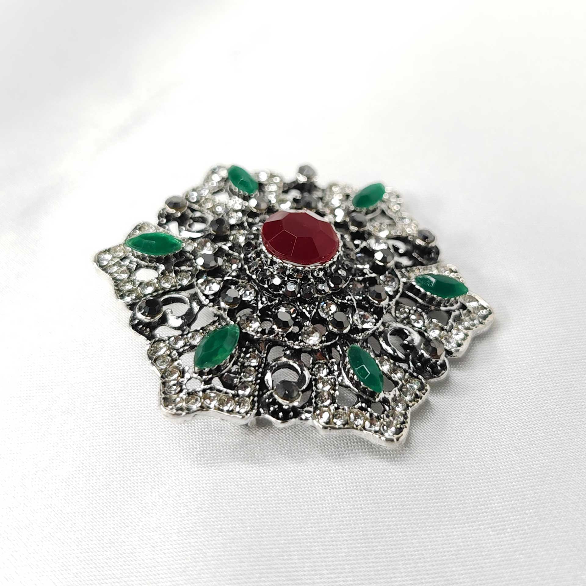 Photo 3 de la broche style baroque a la forme étoilée florale ornée d'un strass rouge centrale.