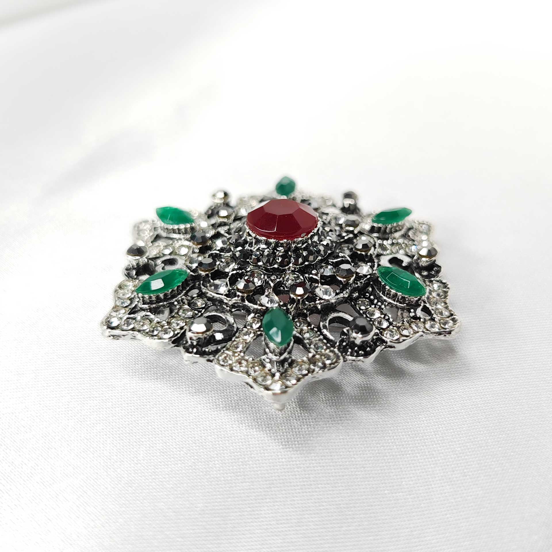 Photo 4 de la broche style baroque a la forme étoilée florale ornée d'un strass rouge centrale.
