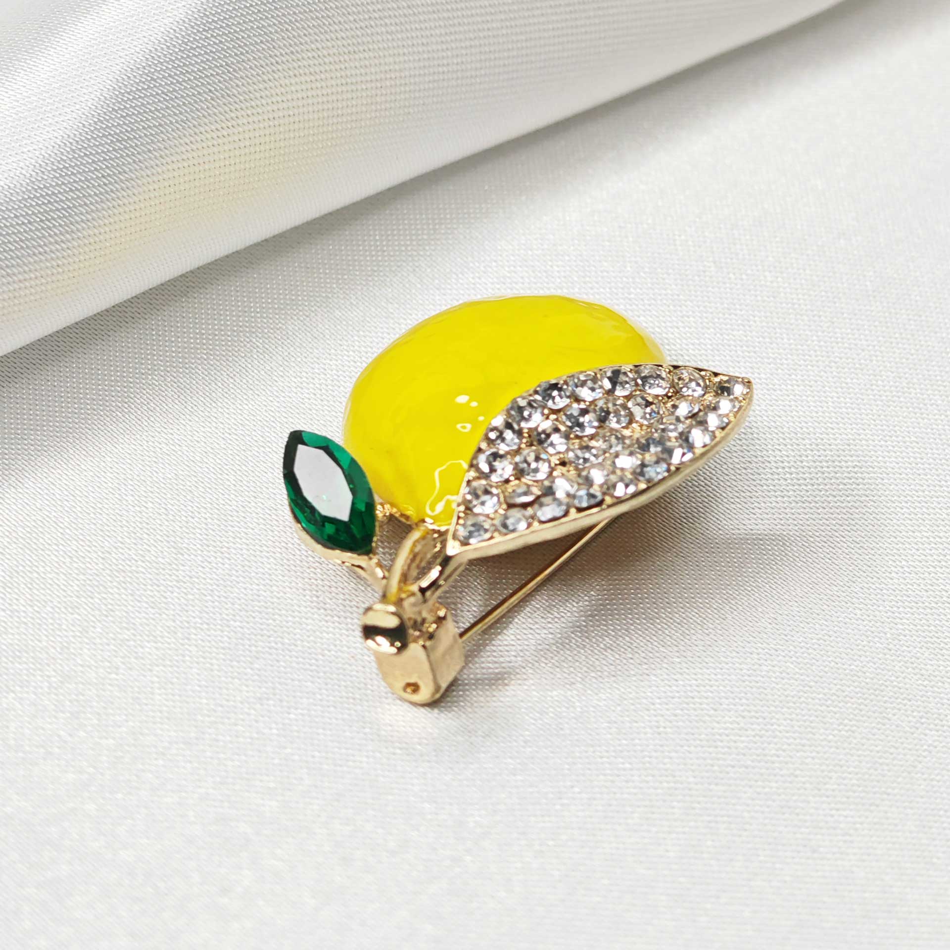Photo zoom sur les strass de la broche citron jaune.