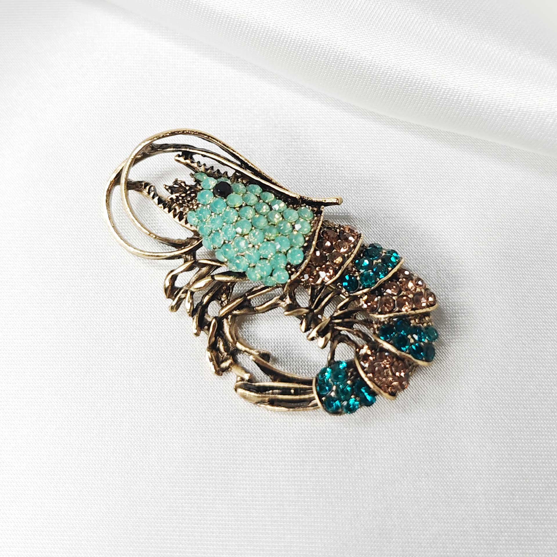 Détail rapproché de la broche crevette bleue, révélant la finesse des antennes et l’éclat des pierres.