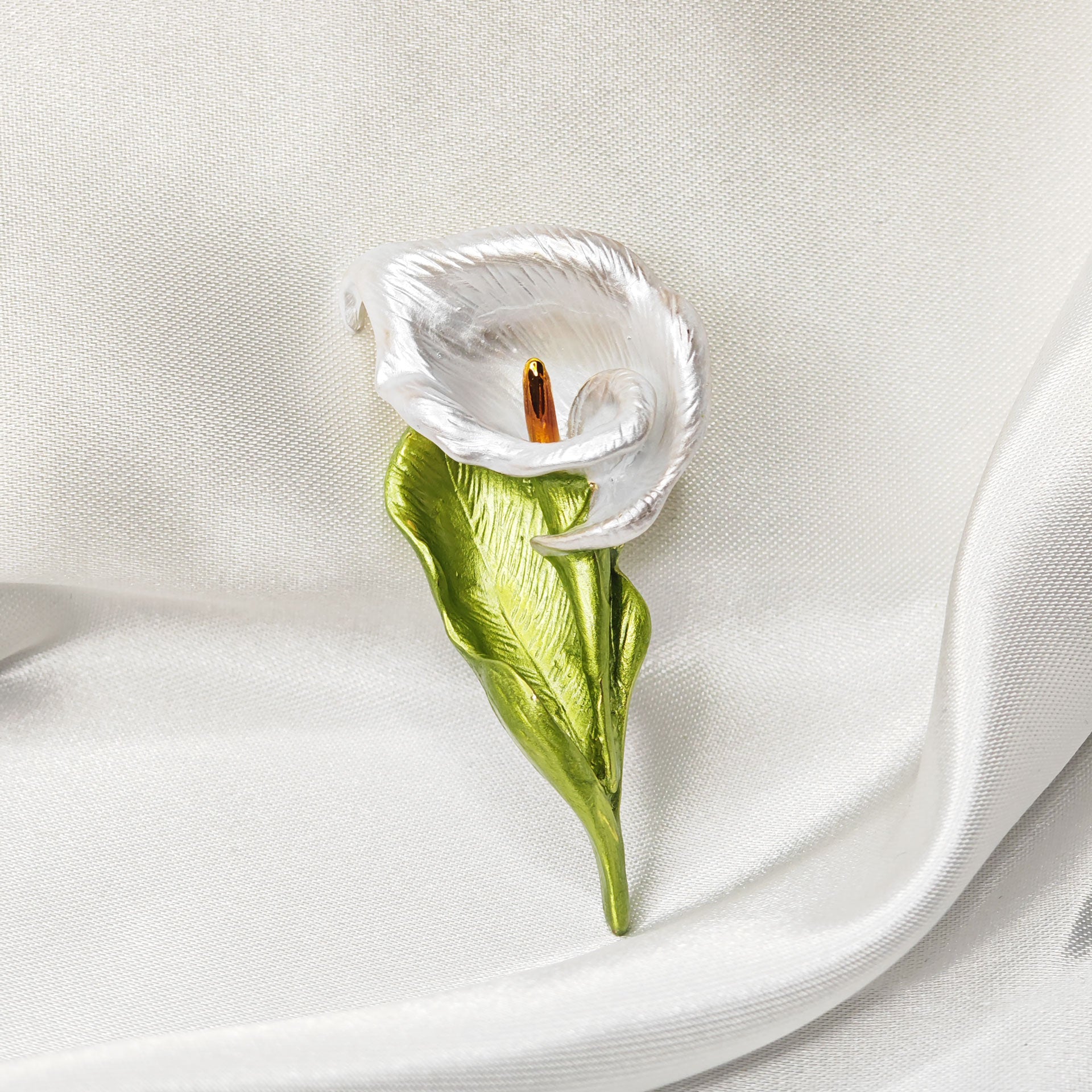 Broche fleur arum blanc et feuille verte sur tissu satiné blanc