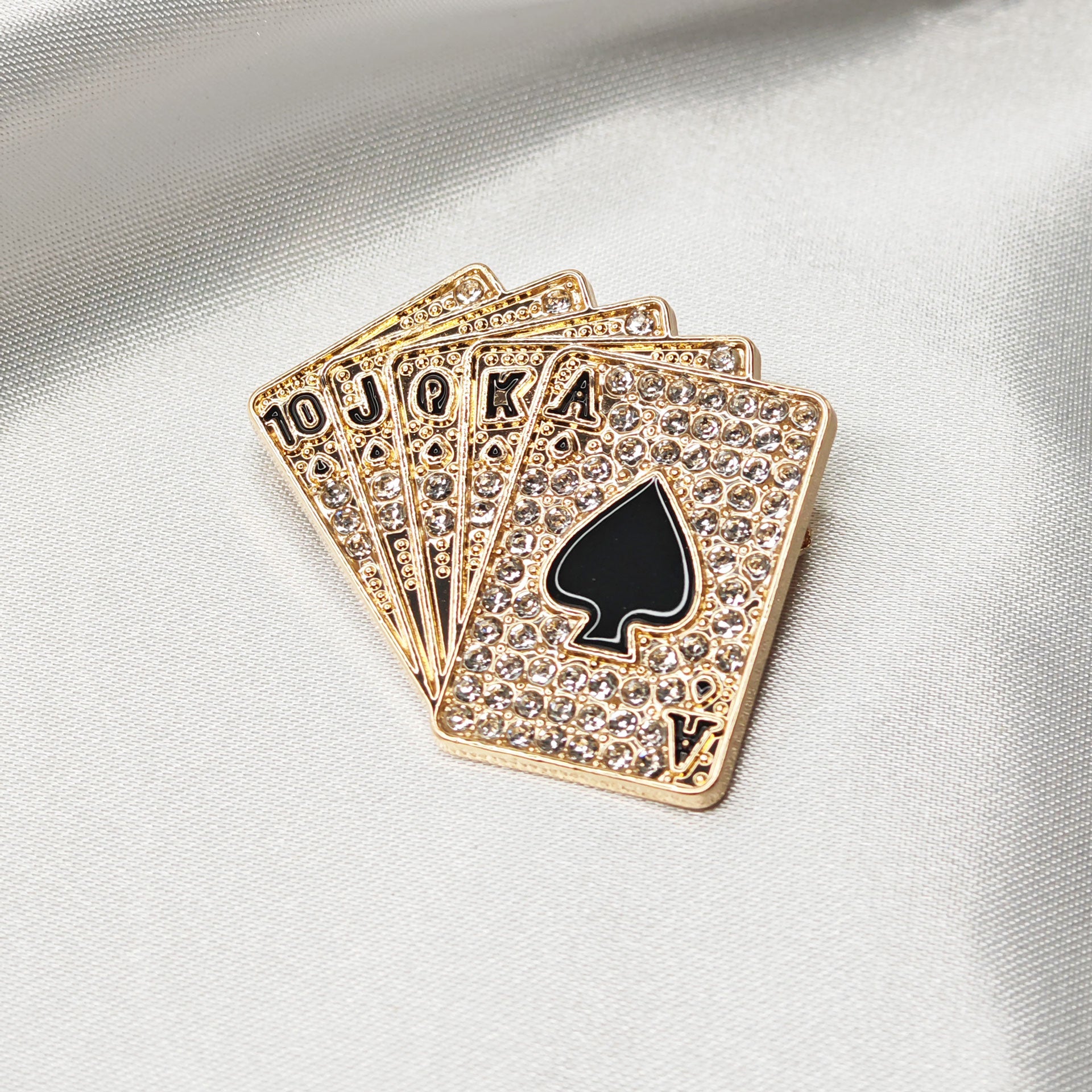 Broche poker Royal Flush dorée en strass sur tissu satiné blanc, as de pique