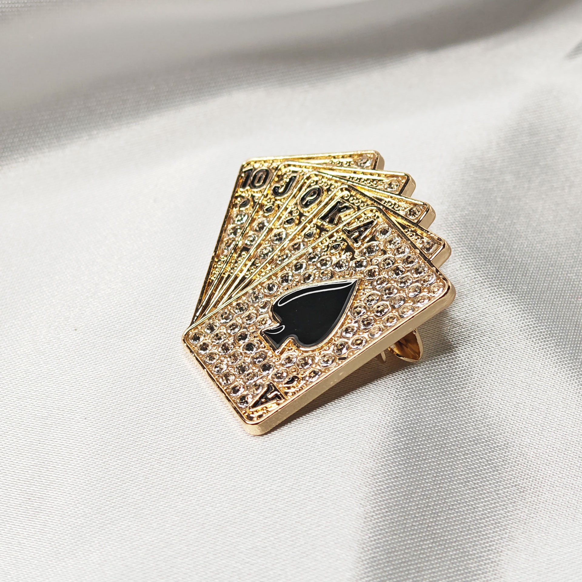 Broche poker dorée vue de côté montrant la finition métallique et les strass