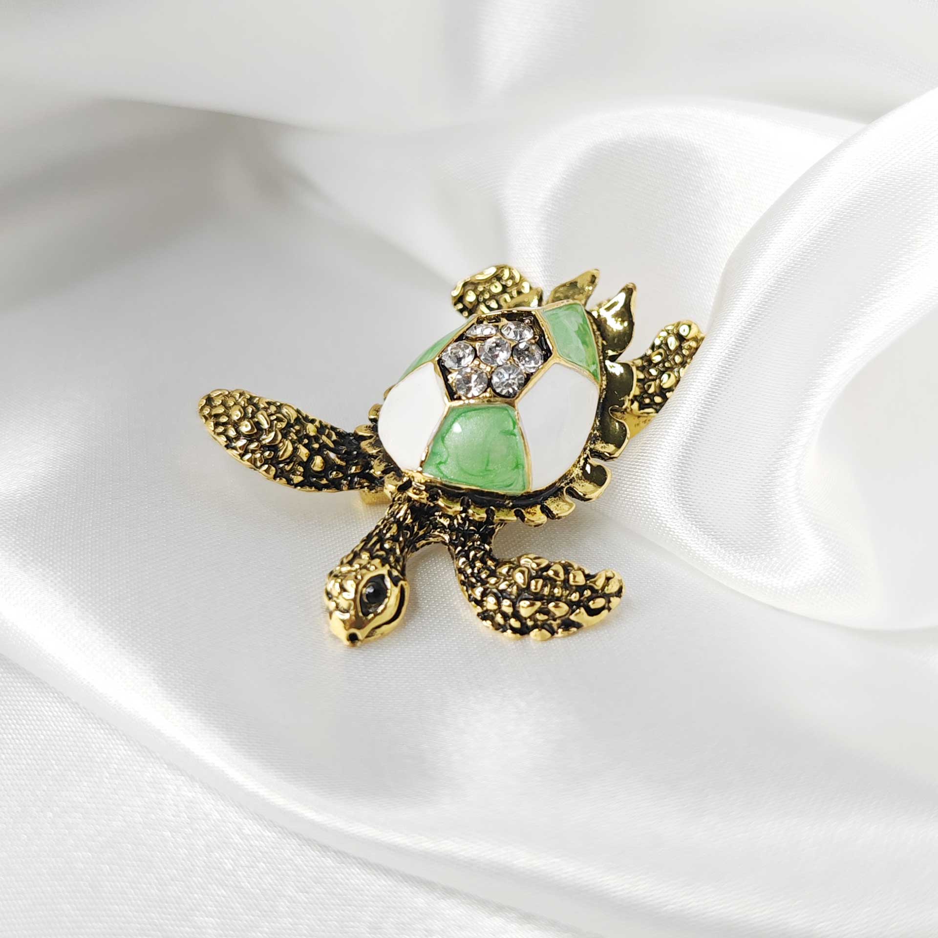 Photo 2 de la broche tortue de mer finition vintage avec une carapace blanche et verte.