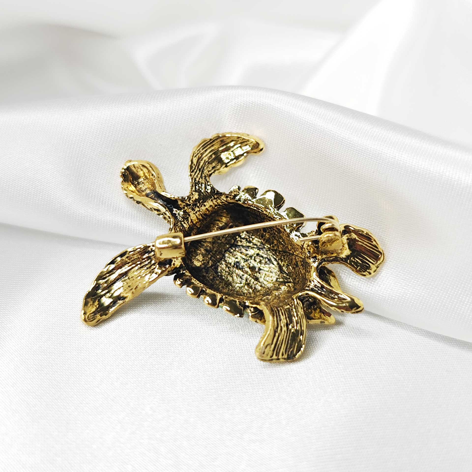 Photo du verso de la broche tortue de mer finition vintage avec une carapace blanche et verte.
