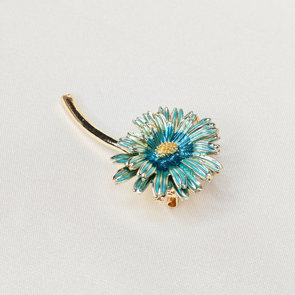 Broche dorée en forme de marguerite de couleur bleue.