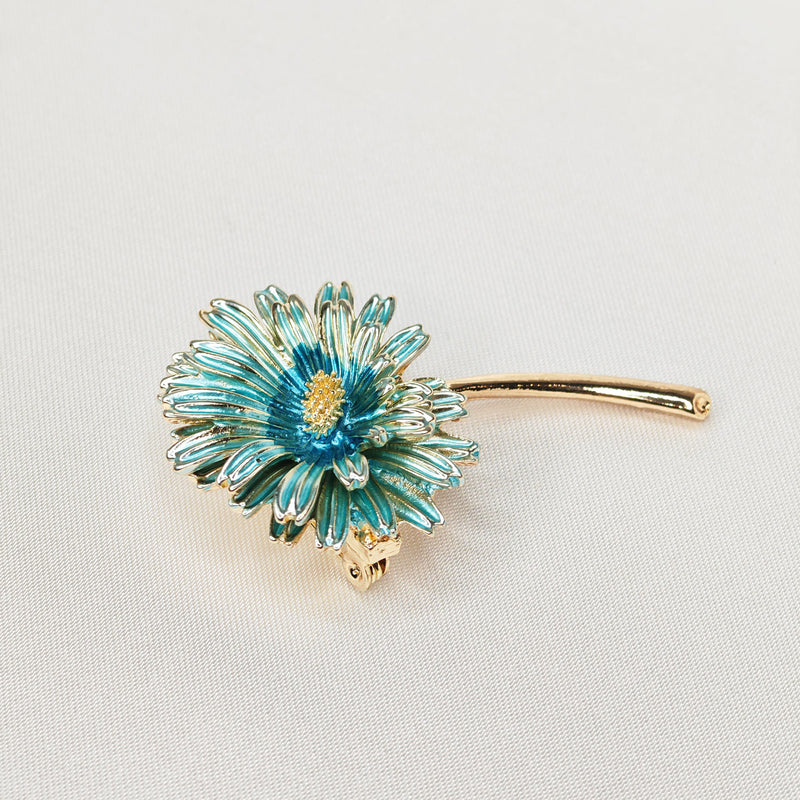 Broche dorée en forme de marguerite de couleur bleue.