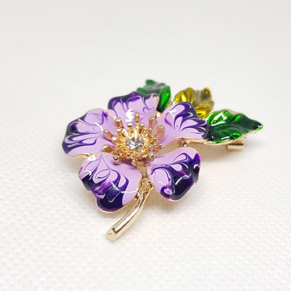 Broche bijou pour femme en forme de fleur violette et pétale verte avec strass en forme de diamant au centre.