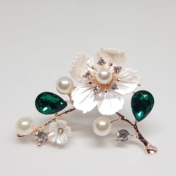 Broche bijou enforme de fleur sur branche avec strass de couleur verte et faux diamants.