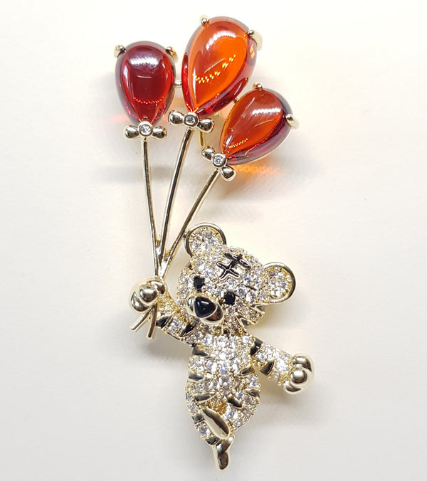 Broche ourson, bijoux pour femme, en forme de petit ourson peluche recouvert de strass style diamant portant 3 ballons couleur rouge orangé.