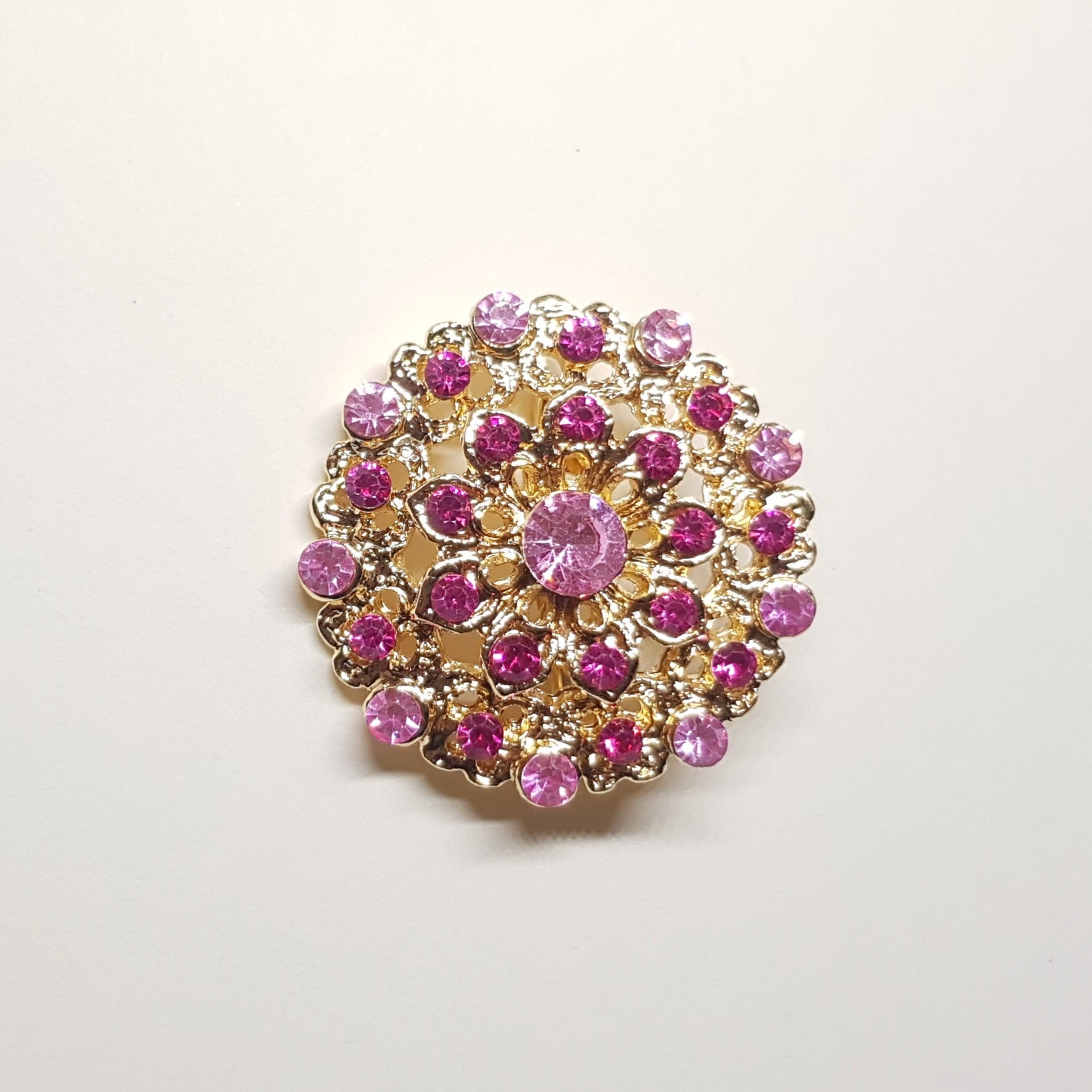 Broche géométrique couleur dorée et strass rose, bijou de vêtement pour femme style vintage élégant.