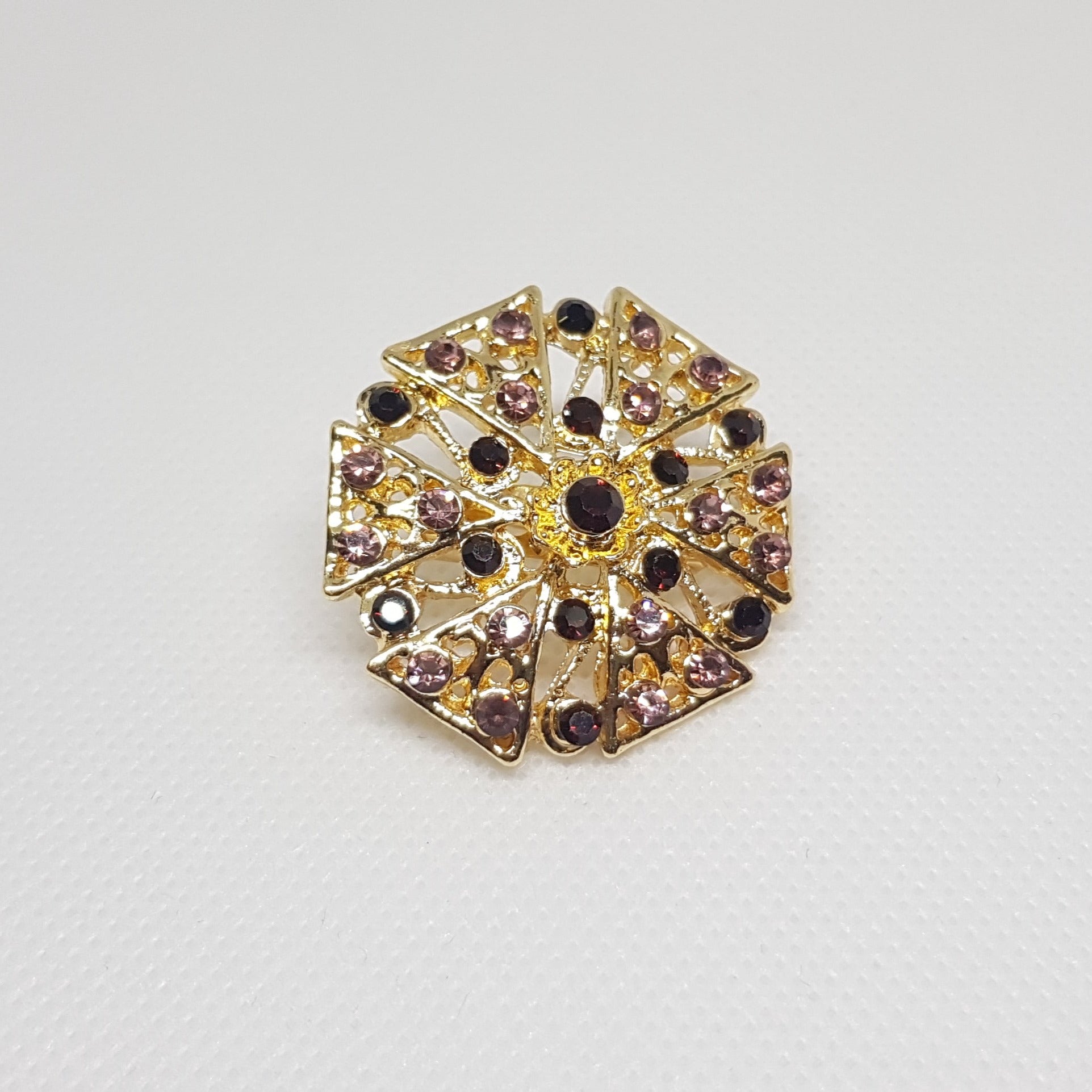 Broche géométrique couleur dorée et strass violet, bijou de vêtement pour femme style vintage élégant.