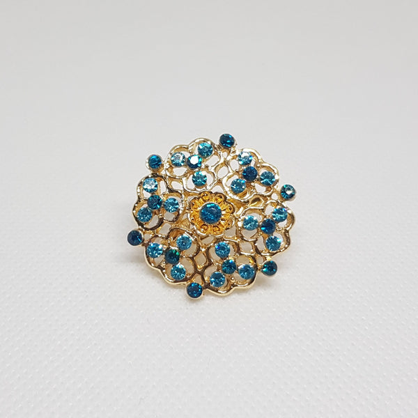 Broche géométrique couleur dorée et strass bleu, bijou de vêtement pour femme style vintage élégant.