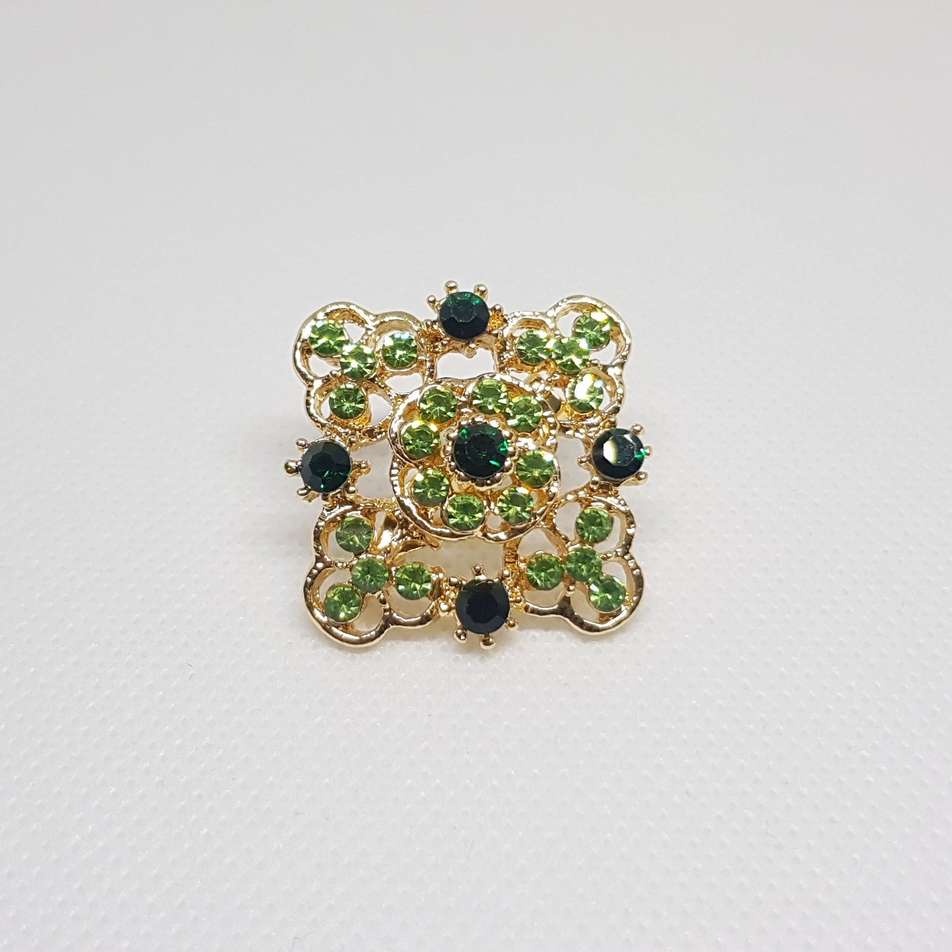 Broche géométrique couleur dorée et strass vert, bijou de vêtement pour femme style vintage élégant.