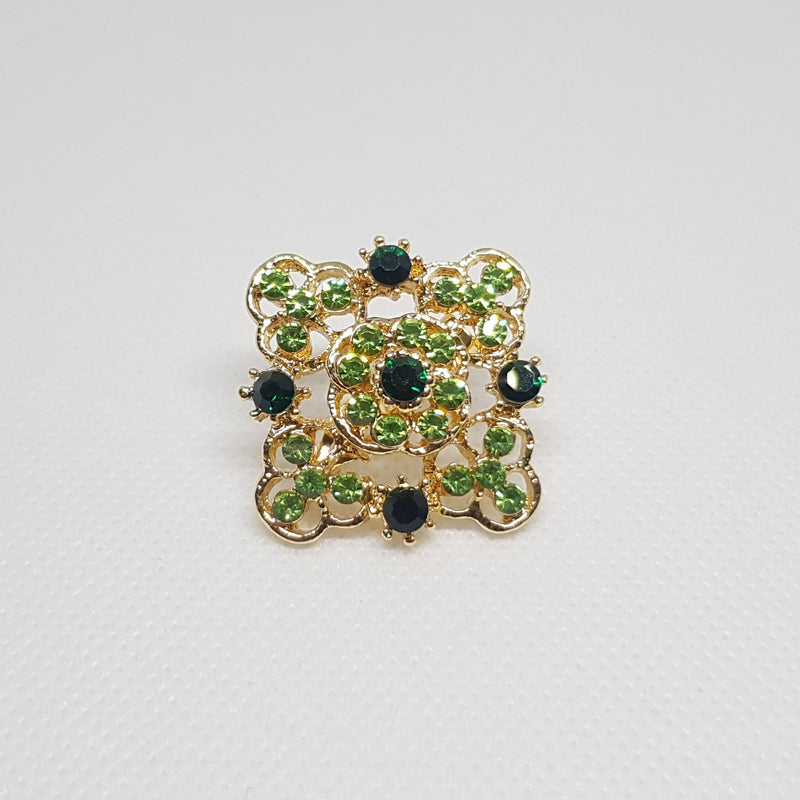 Broche géométrique couleur dorée et strass vert, bijou de vêtement pour femme style vintage élégant.