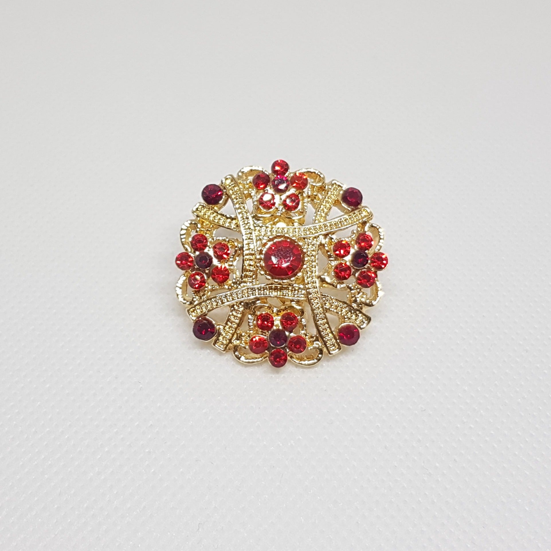 Broche géométrique couleur dorée et strass rouge. Bijou de vêtement pour femme style vintage élégant.