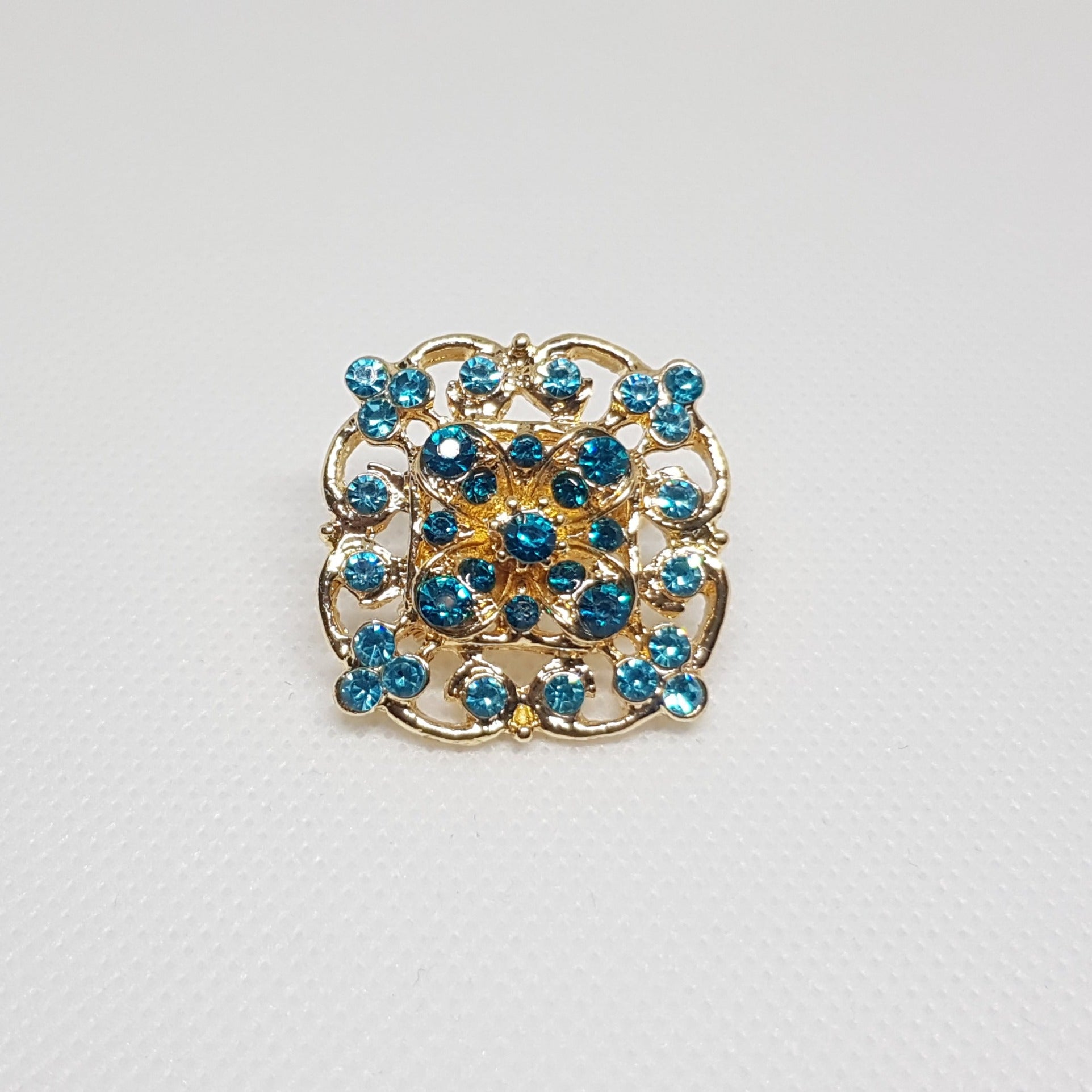 Broche géométrique couleur dorée et strass bleu. Bijou de vêtement pour femme style vintage élégant.