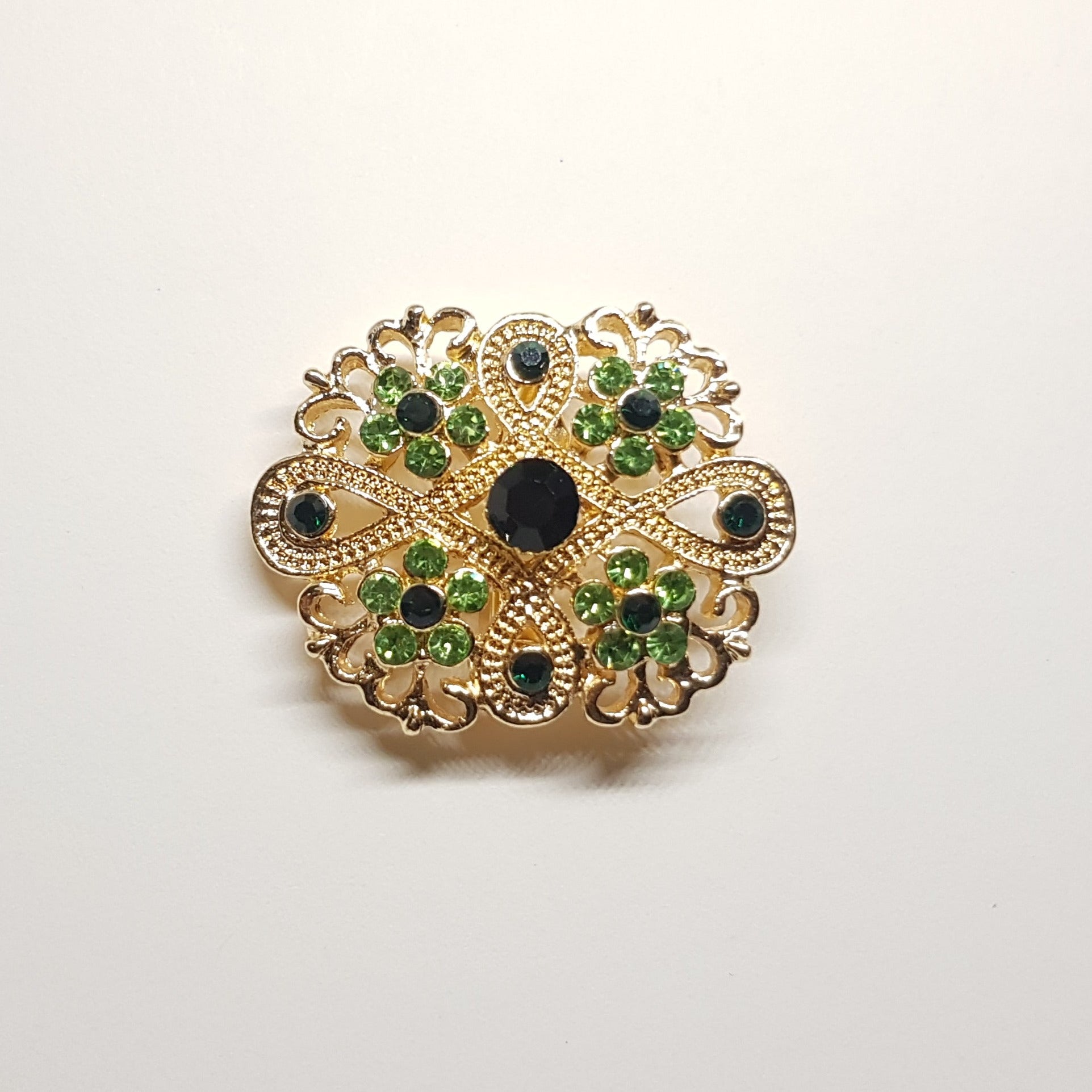 Broche géométrique couleur dorée et strass vert, bijou de vêtement pour femme style vintage élégant.