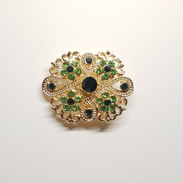 Broche géométrique couleur dorée et strass vert, bijou de vêtement pour femme style vintage élégant.