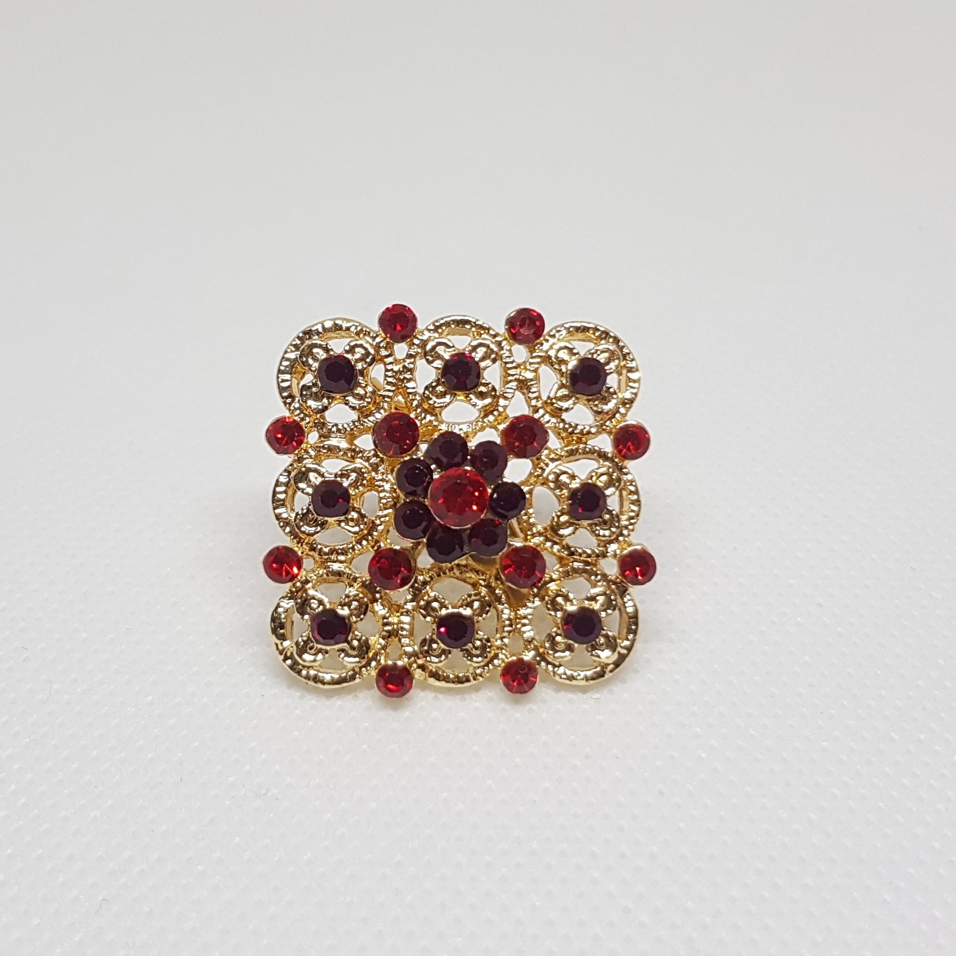 Broche géométrique couleur dorée et strass rouge. Bijou de vêtement pour femme style vintage élégant.