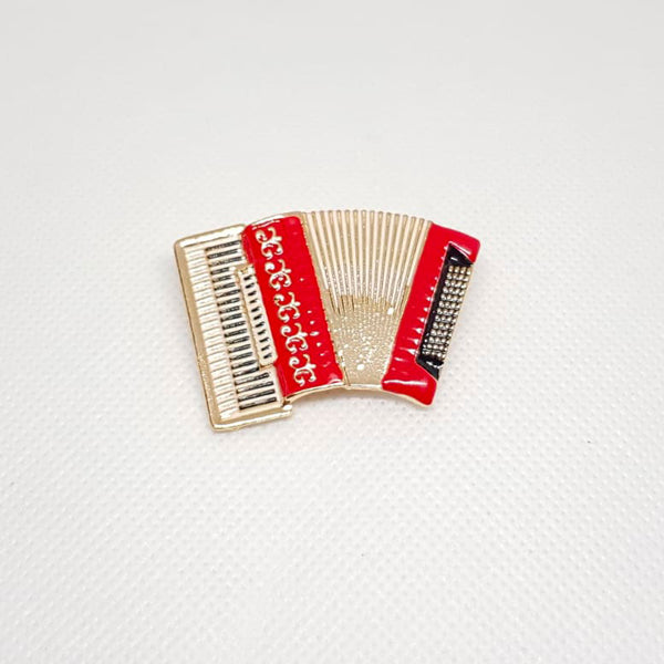 Broche dorée en forme d'accordéon de musique couleur rouge.