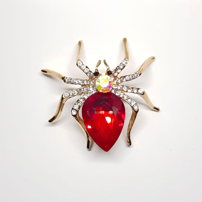 Broche dorée en forme d'araignée rouge avec strass effet diamanté.