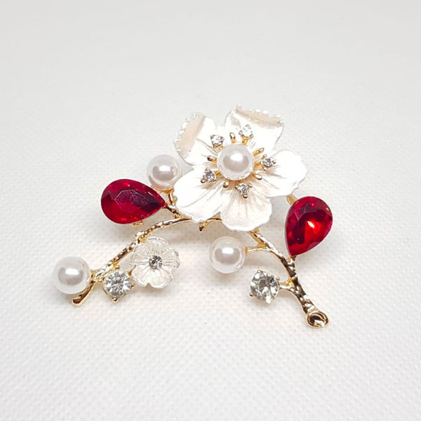 Broche de mariage en forme de fleur sur une blanche avec perles et cristal rouge et strass.