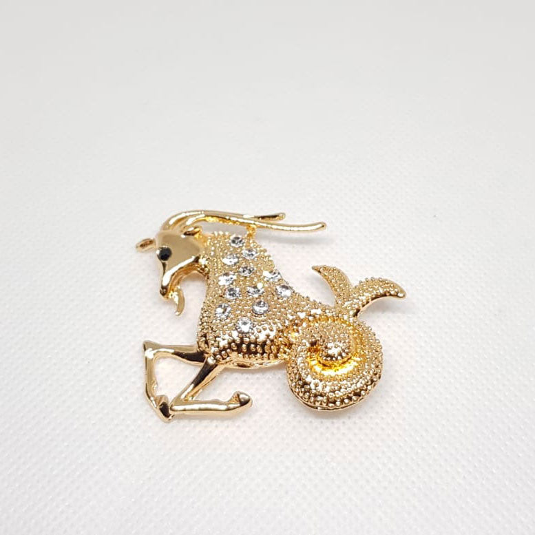 Broche dorée en forme de signe du zodiaque Capricorn avec strass effet diamanté.