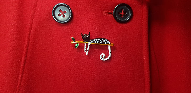 Broche Chat Perché sur un manteau rouge.