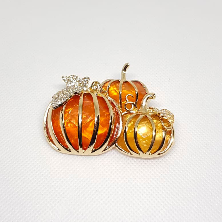 Broche dorée en forme de trois citrouilles avec strass effet diamanté.