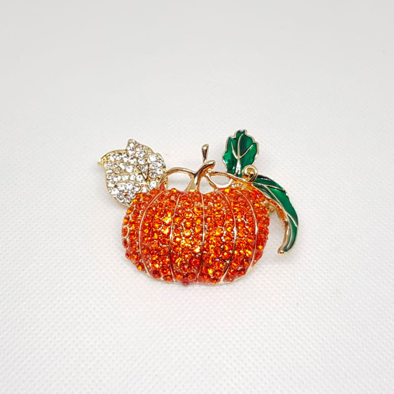 Broche dorée en forme de citrouille avec strass orange et blanc effet diamanté.