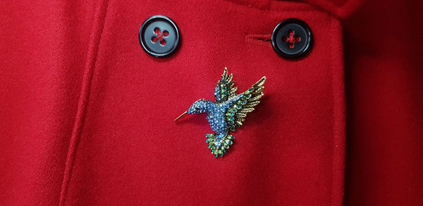 Broche Colibri sur manteau rouge.
