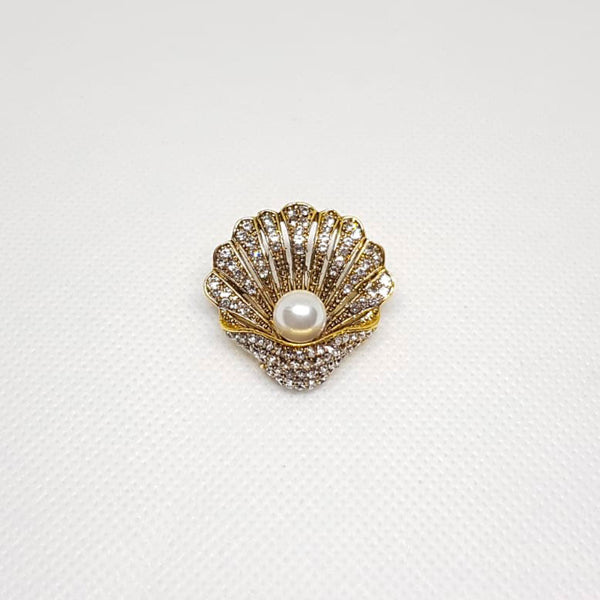 Broche dorée en forme de coquillage avec une perle à l'intérieur.