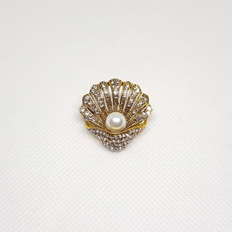 Broche dorée en forme de coquillage avec une perle à l'intérieur.