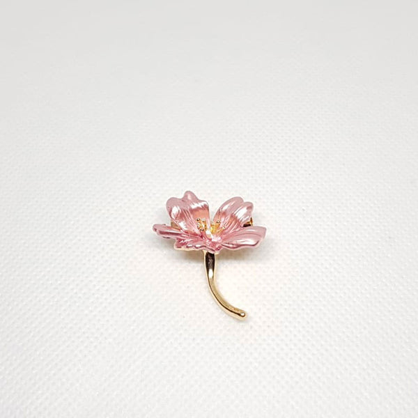 Broche dorée en forme de petite fleur rose.