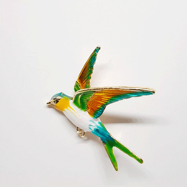 Broche dorée en forme d'oiseau hirondelle multicolore en plein vol 