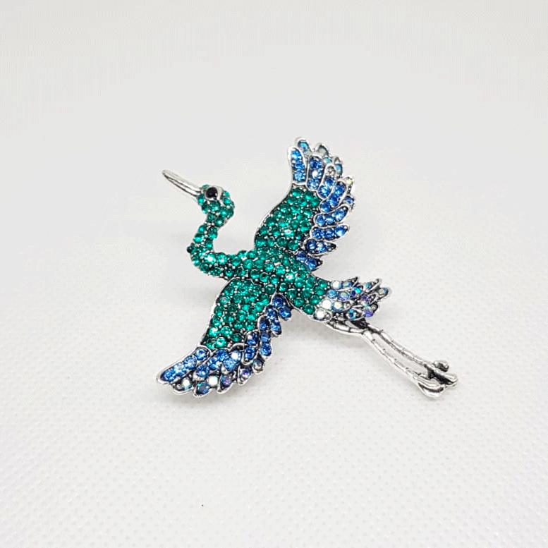 Broche argentée en forme de Héron de couleur bleu vert.